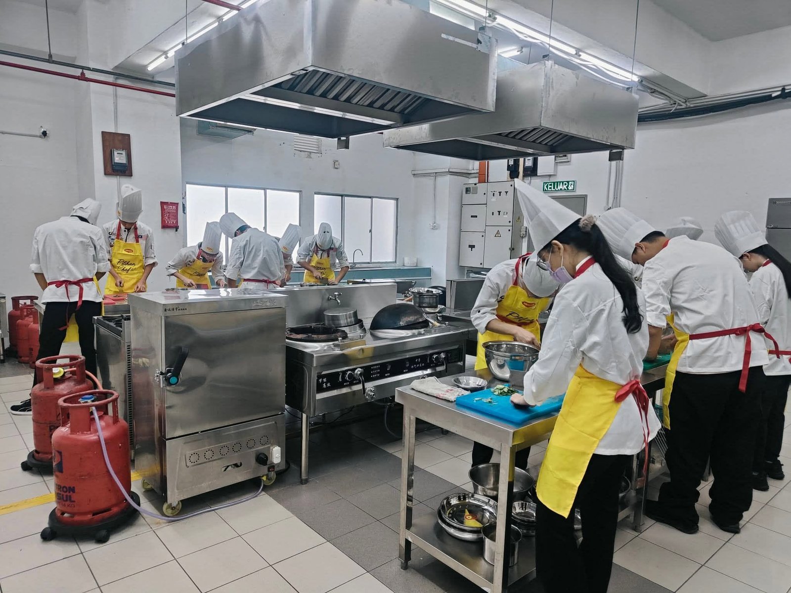 Asian culinary student practicing in professional kitchen；亚洲厨艺学生在专业厨房实操